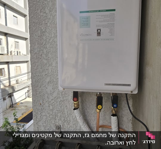 דוד שמש מותקן על קיר חיצוני עם צינורות חיבור